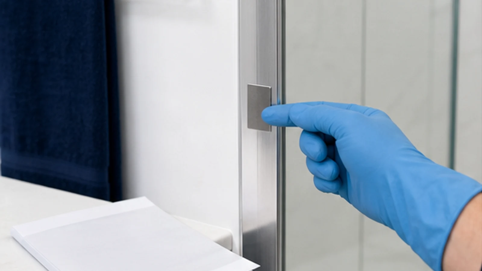 A spray bottle applying liquid to a lower corner of shower glass in a test area