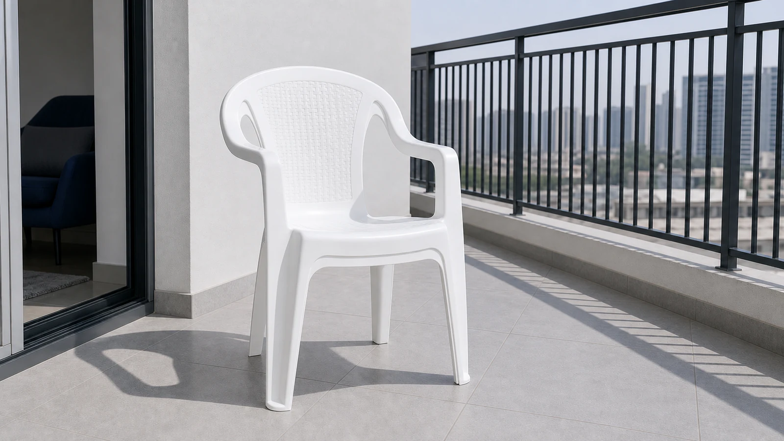 A white plastic chair standing alone on a sunny balcony, visibly dry and bright white, with natural daylight casting a soft shadow.