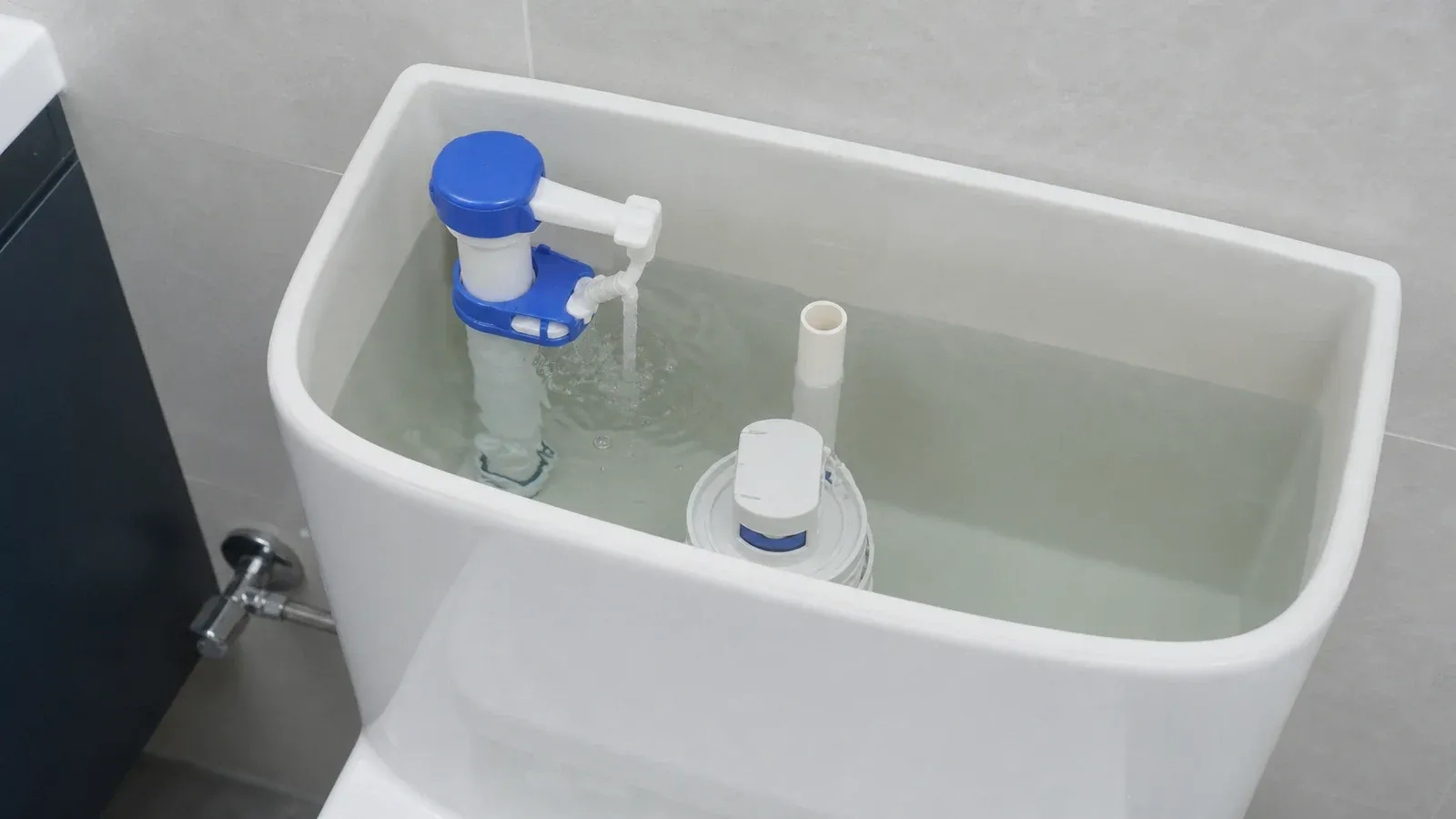 Hand adding a few drops of food colouring to the water in an open gravity cistern without touching the mechanism